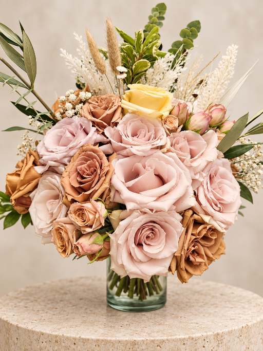Rounded bridal bouquet of blush and toffee roses with pampas and eucalyptus.