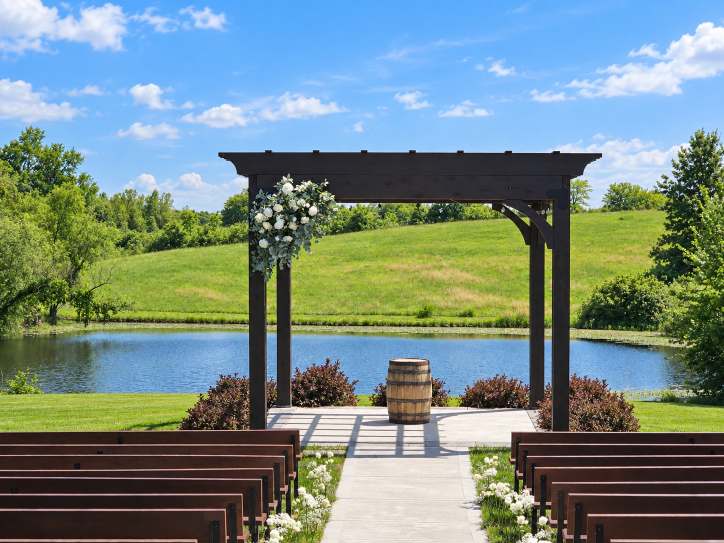Outdoor ceremony arch dressed with flowers overlooking a lake.