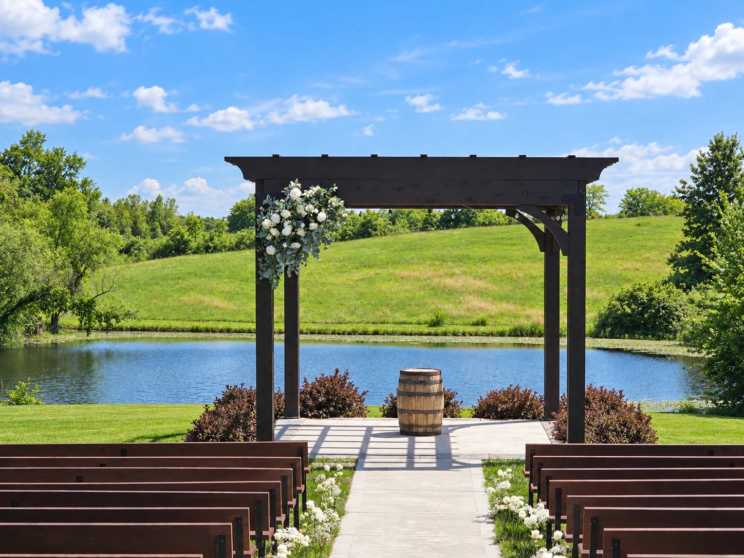 Outdoor wedding ceremony with a wooden pergola dressed in flowers beside a pond.