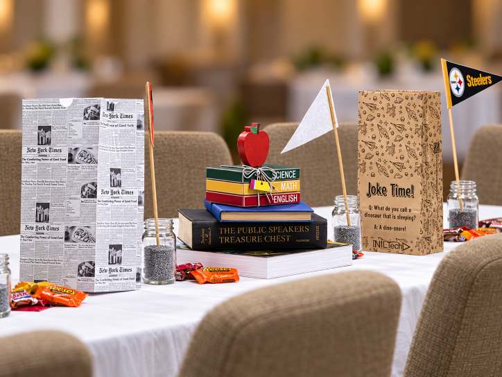 Graduation-themed table setting with books, apples and flowers.