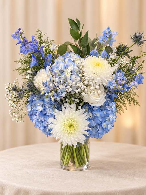 Blue and white floral arrangement with hydrangea and roses.