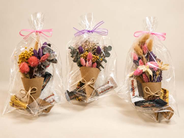 Three wrapped mini bouquets, each with a chocolate bar attached.